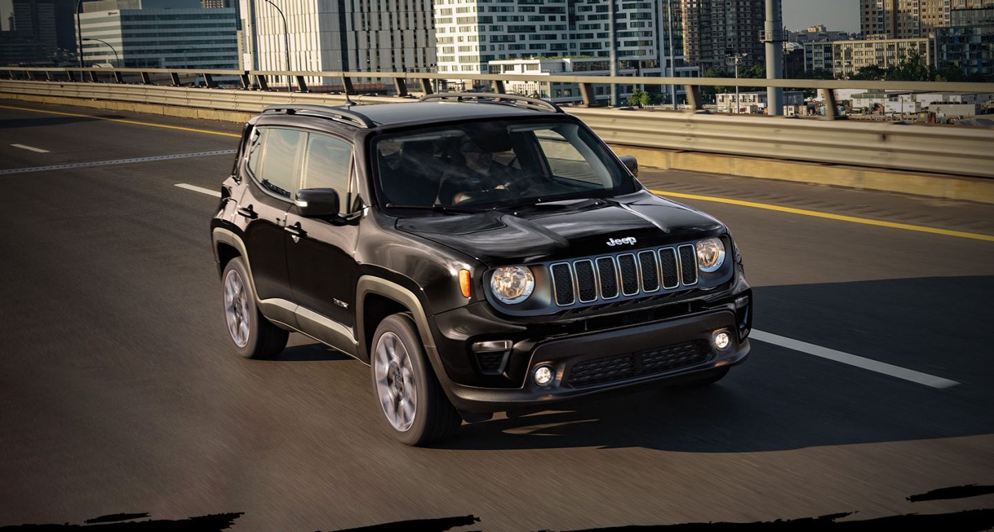 The 2022 Jeep Renegade Limited being driven on an overpass with a city view behind it. The Jeep Celebration Event logo.