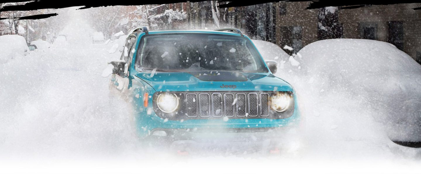 The 2022 Jeep Renegade Trailhawk being driven in falling snow, its wheels obscured by snow.
